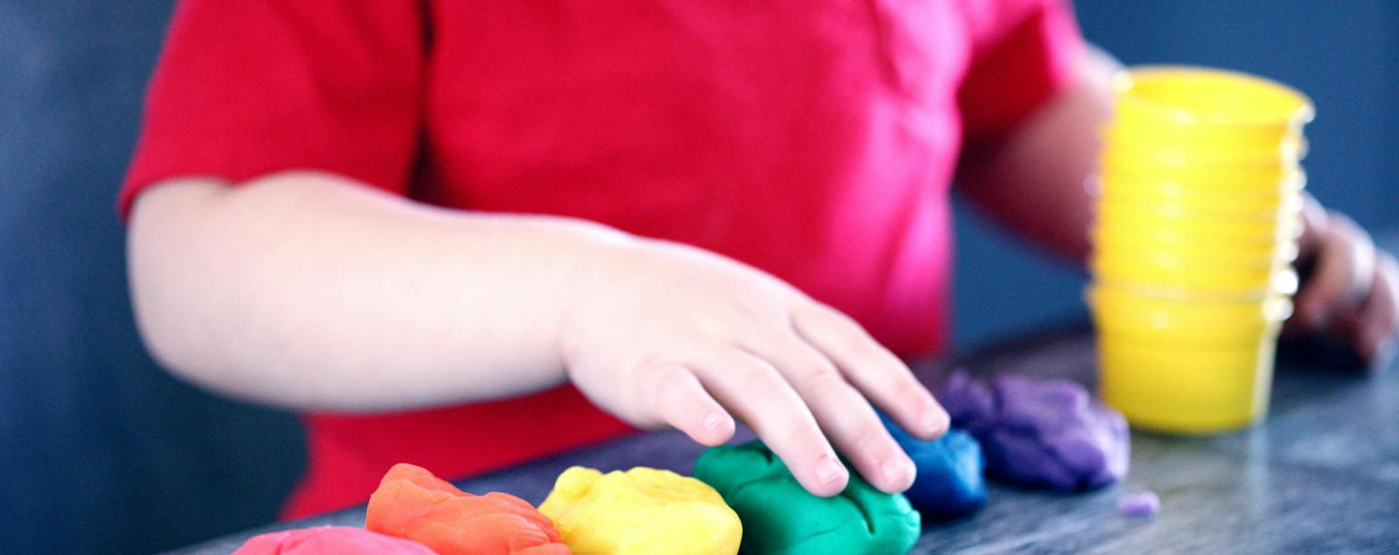 Image of a child playing with clay on a table